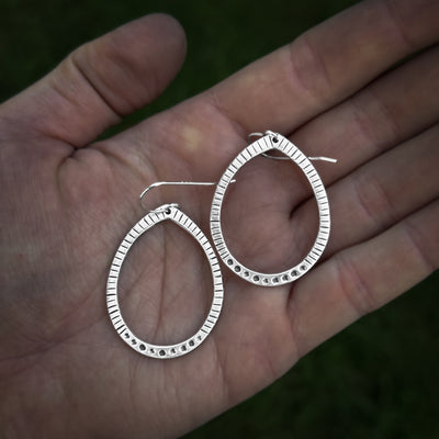 Silver textured teardrop earrings being held in a hand, handcrafted in my jewelry studio in Brattleboro, Vermont