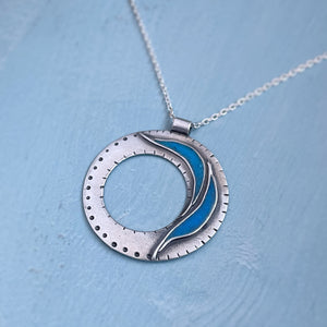 Flowing Open Silver Necklace circle with hole in middle with two blue currents made from turquoise. Dot and line markings on the outside. On light blue background. Empowering jewelry, healing jewelry, handmade in Vermont. 