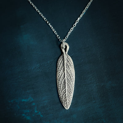 Silver Sage Leaf Necklace on Silver chain on blue background.