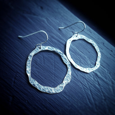 Silver Aura Earrings hammered silver hoops on blue background empowering jewelry handmade vermont